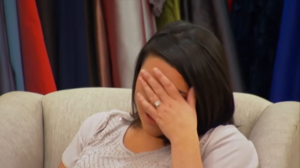 Bride breaking down in tears discussing her absent mother during a bridal fitting.