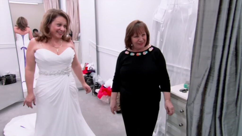 Emotional bride looking in the mirror at her custom wedding gown.