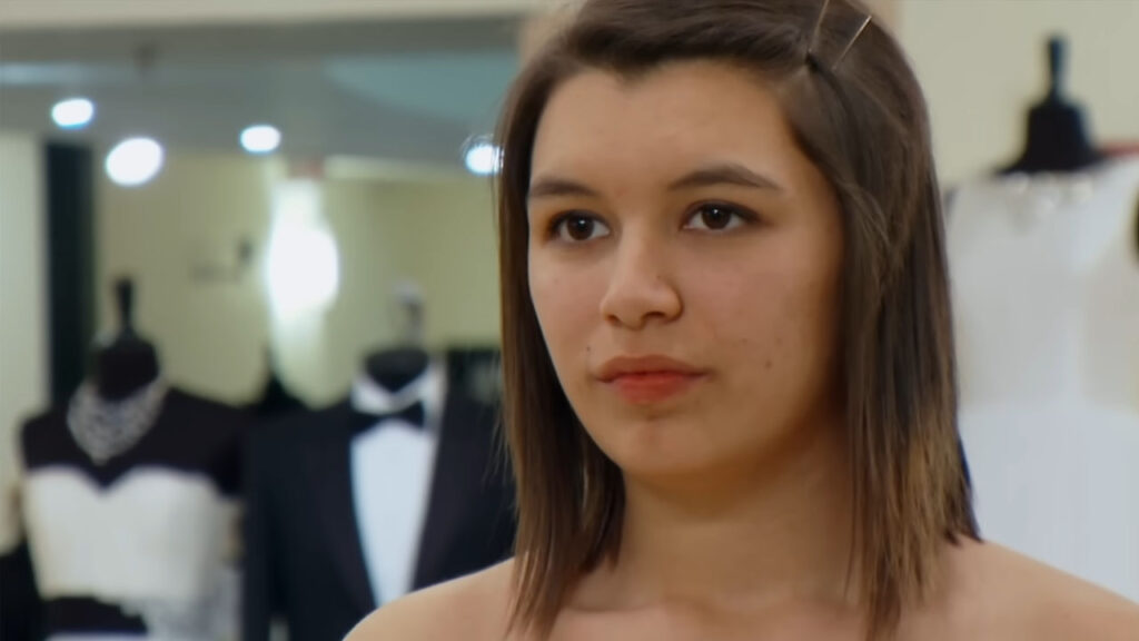Frustrated young bride at a luxury bridal boutique trying to please her parents.